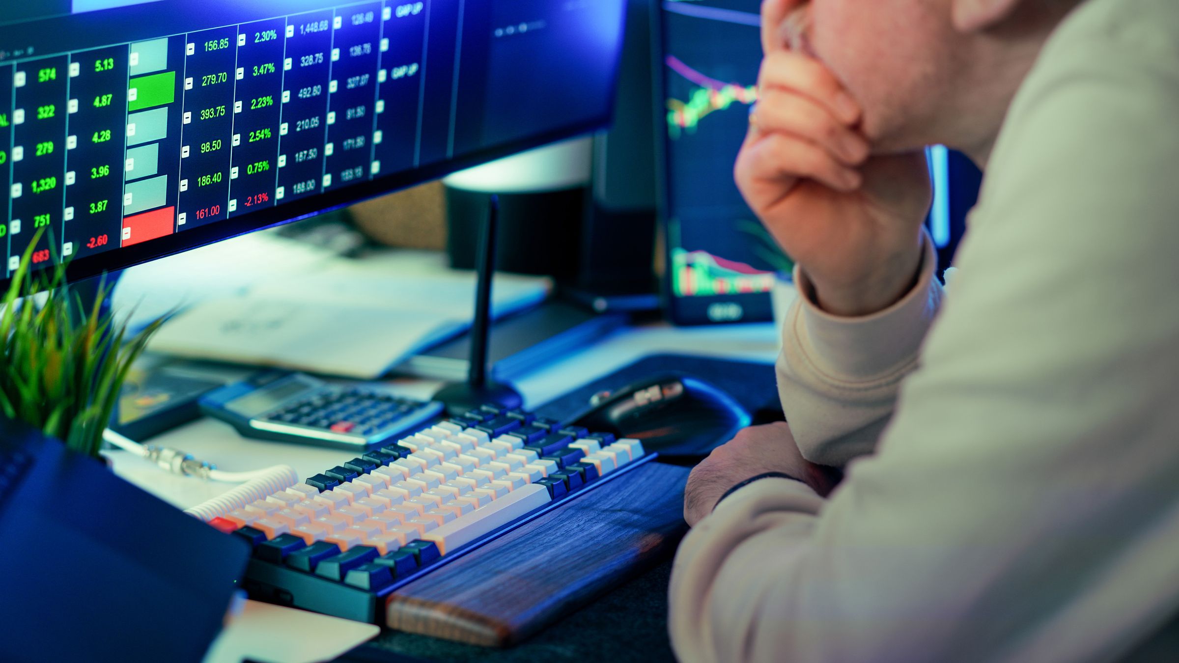 Close-up of hands on a keyboard with trading dashboards in the background